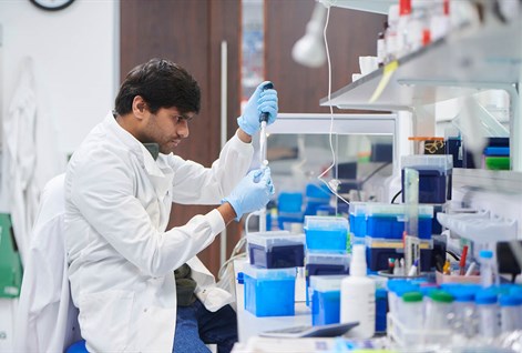 Scientist in a white lab coat testing samples in a lab