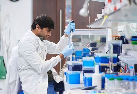 Scientist in a white lab coat testing samples in a lab