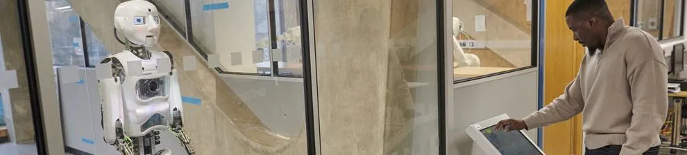 Man programing humanoid robot in lab