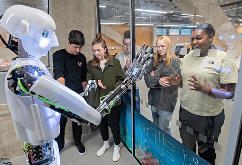 Small group of student looking at robot man
