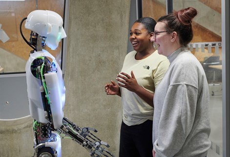 Students standing next to AI robot