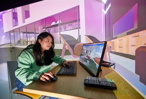 Student working on a screen with large image projected behind her