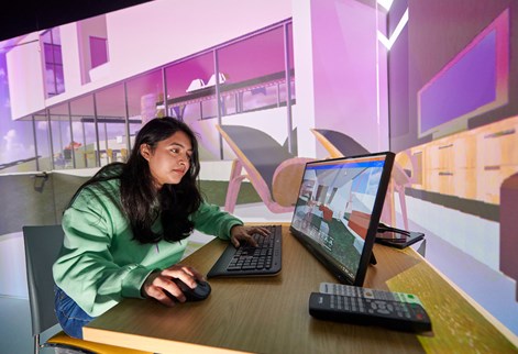 Student working on a screen with large image projected behind her