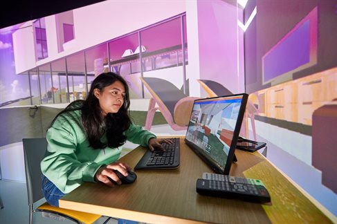 Student working on a screen with large image projected behind her
