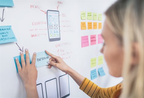 female pointiing at design wall chart