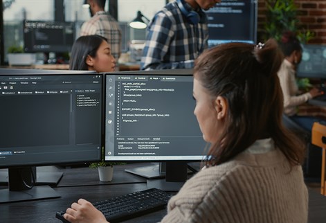 Student with two screens of computer code