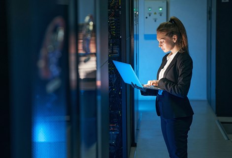 IT professional on a laptop in a server room