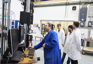 Civil engineering students and technician using heavy concrete testing equipment