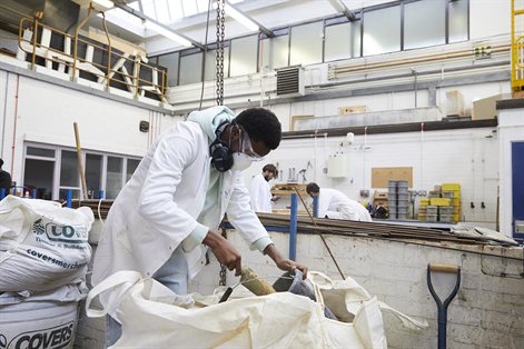 Male civil engineering student with mask on mixing concrete