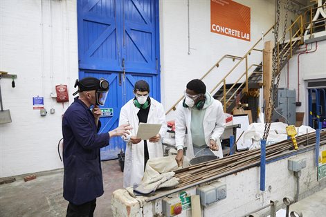 Technician talking to two civil engineering students in concrete lab