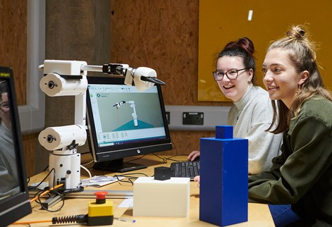 Two female students using robot arm
