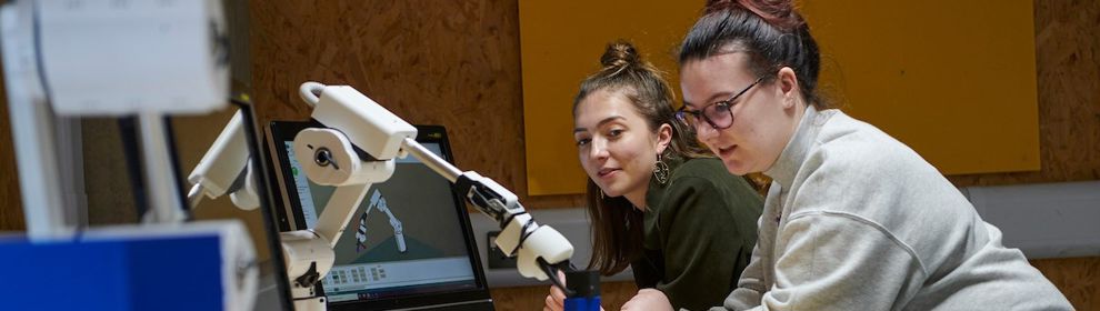 Two students working with the robotic arm