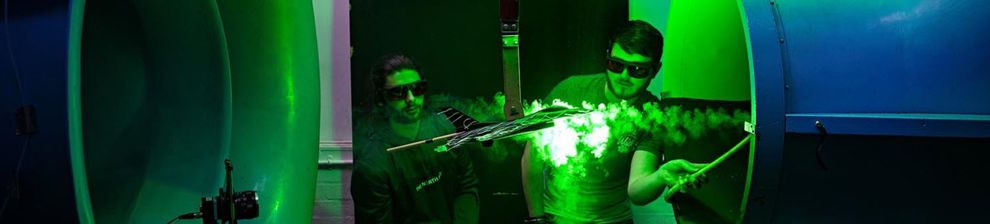 Two students doing an engineering experiment in the wind tunnel using smoke and green light