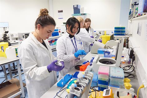 Three female students with female lecturer in ecology lab