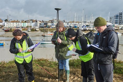 four students in a harbour with clipboards