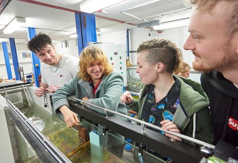 Four students looking over a flume in the hydraulics lab