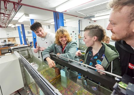 Four students looking over a flume in the hydraulics lab
