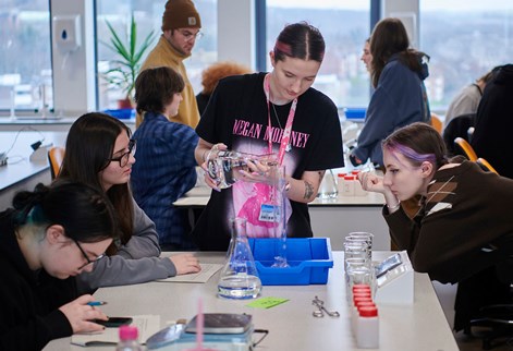 Students doing group work in a geography lab puring water into a large glass container