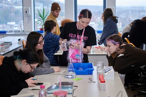 Students doing group work in a geography lab puring water into a large glass container