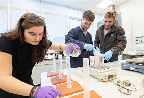 Two geography students on placement working with colleague in lab