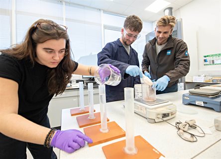 Two geography students on placement working with colleague in lab