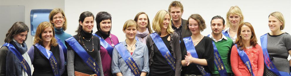 A line of masters students all wearing blue sashes