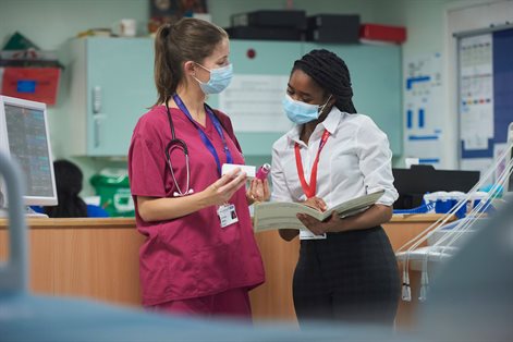 Female in scrubs talking to female placement student