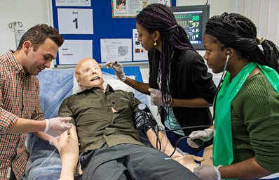 Three students attending to a synthetic patient in bed