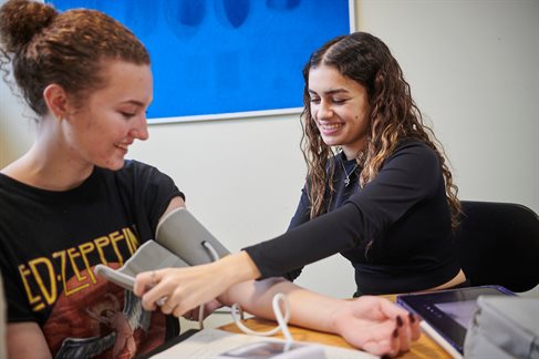 Pharmacy student taking another students' blood pressure