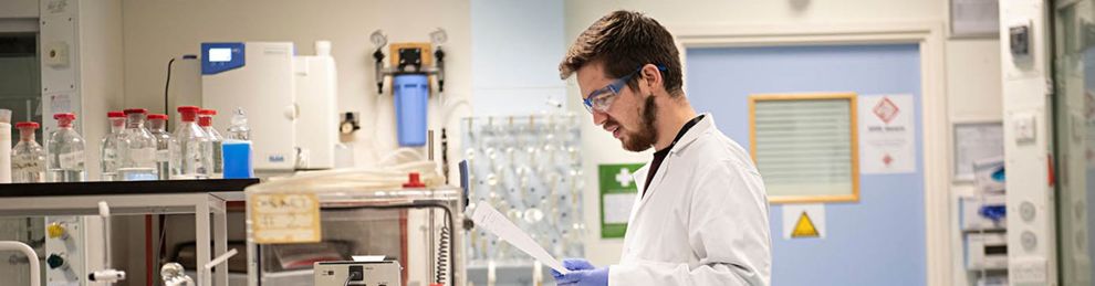 Student reading paper in chemistry lab