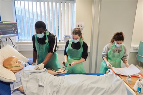 Three students working with simulation dummy