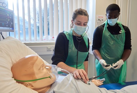 Two pharmacy students using stethoscope on SIM Man patient simulation dummy