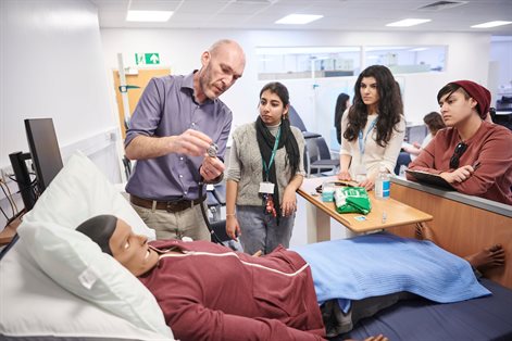 Pharmacist teaching students stood around a hospital bed