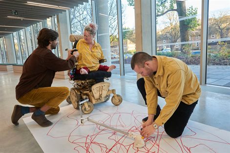 Three people, one a wheelchair user, creating a drawing