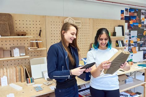 Two design students laughing together in studio