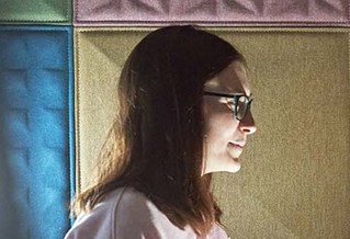 Lady standing with multi-coloured wall behind her