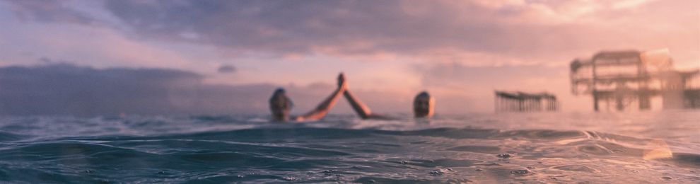 Two people swimming by the west pier