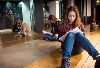 Student sitting on the floor of a gallery while writing