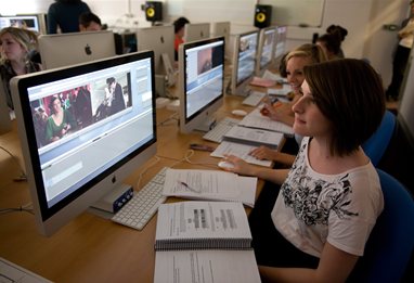 A row of five computers with students editing films