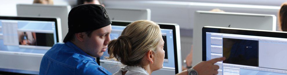 Two people having a discussion in front of some computer screens