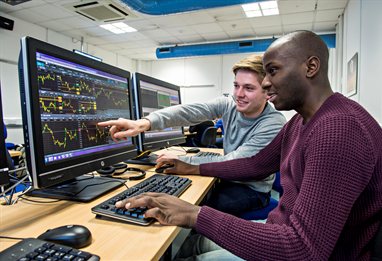 Two students comparing graphs on computer screens