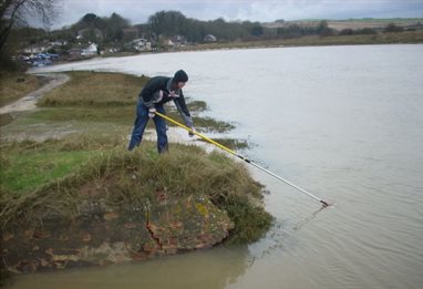 Student researching water quality on the water's edge