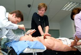Three students working on a dummy patient