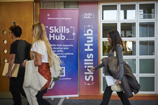 Students walking in front of a sign for the Skills Hub