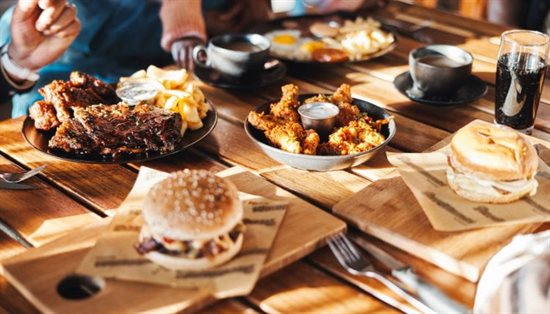 A table with an assortment of food including burgers and chicken wings