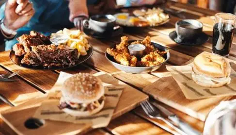 A table with an assortment of food including burgers and chicken wings