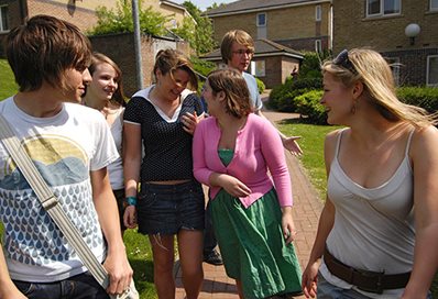 A group of students walking the path outside some halls of residence