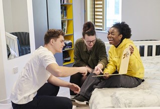 Three students laughing in halls