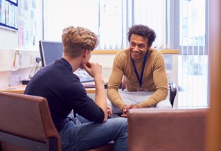 Male Student Meeting With Counselor Discussing Mental Health Issues