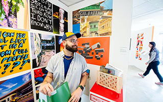 Student standing in front of a wall of colourful artworks.